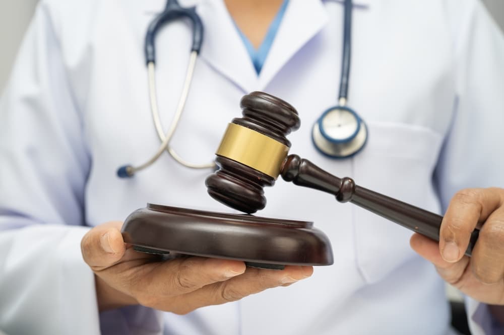 Doctor holding judge gavel - Concept of Medical Malpractice Law