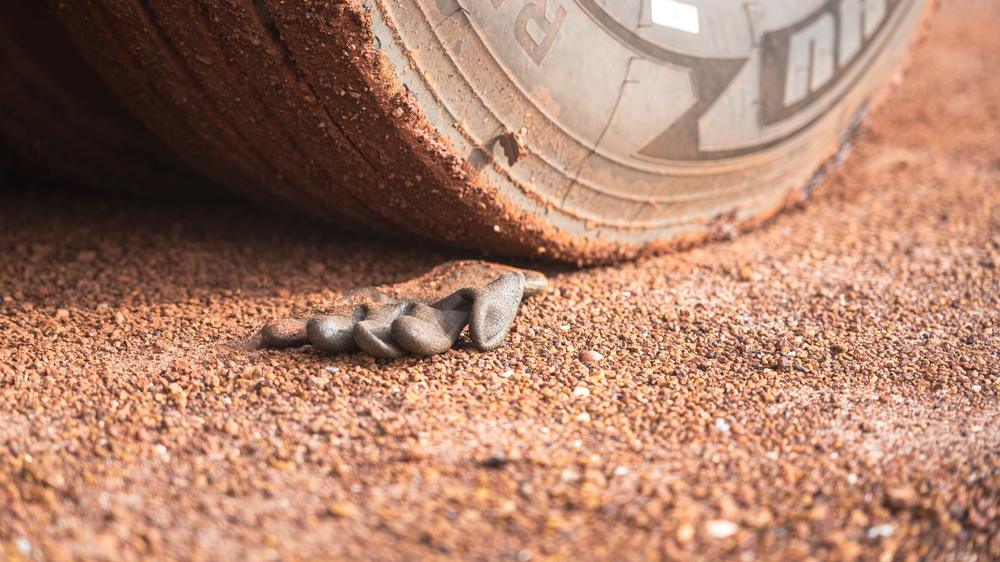 Work glove under heavy construction vehicle tire showing crush injury risk on NYC job sites