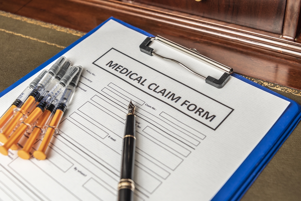 Medical claim form on clipboard with syringes and pen used for documenting workplace injury treatment