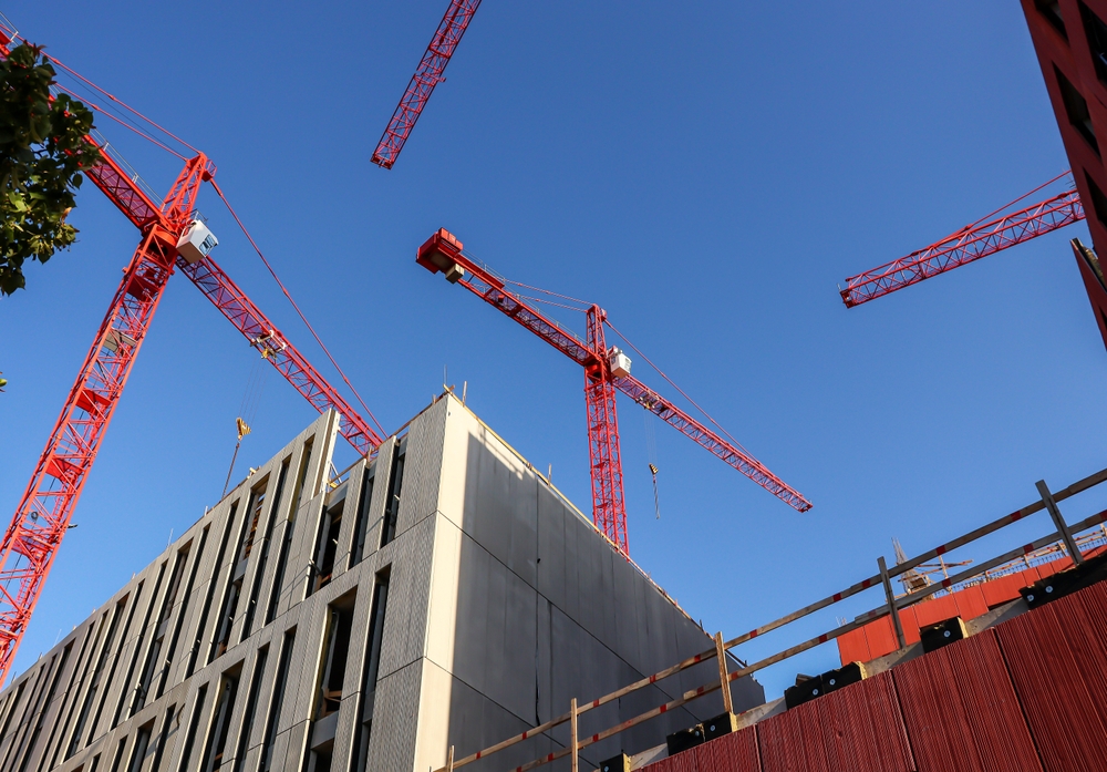 NYC construction site with multiple red cranes, illustrating risks that may require hiring a construction accident lawyer