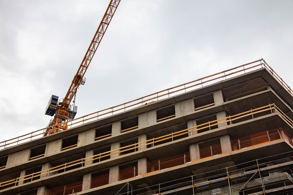 A crane operating above a multistory building under construction in New York, representing potential parties liable in construction accidents.