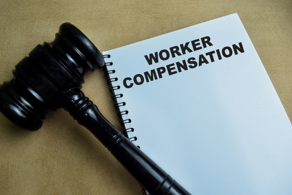 Workers’ compensation notebook with judge’s gavel representing legal implications of OSHA reporting and injury documentation