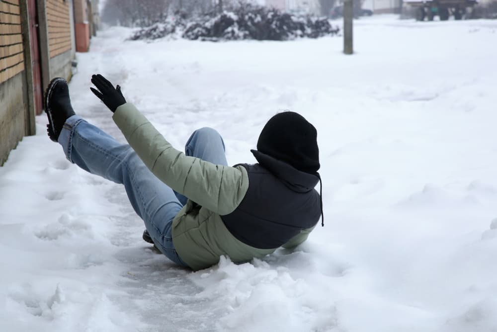 A woman slips on an ice-covered road